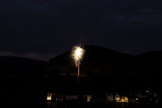 A firework rocket in the sky on a mountain at night, a few illuminated houses in the foreground,A firework rocket in the sky on a mountain at night, a few illuminated houses in the foreground