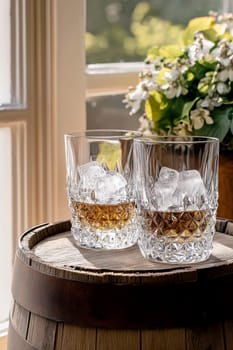 Two elegant, crystal-clear glasses of whiskey with ice cubes. AI generative.
