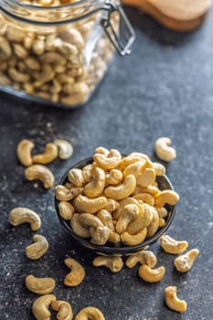 Roasted cashew nuts in bowl on a black table.