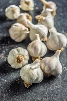 Unpeeled garlic bulbs cloves on a black table.