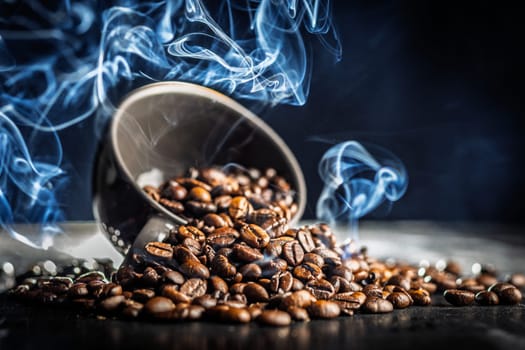 Roasted coffee beans in cup with smoke on a black table.