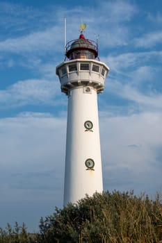 The approx. 28 m high white lighthouse J.C.J. van Speijk in Egmond aan Zee, North Holland, Netherlands, in the sand dunes with beach grass