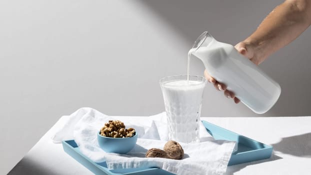 person pouring milk full glass with walnuts tray . Resolution and high quality beautiful photo