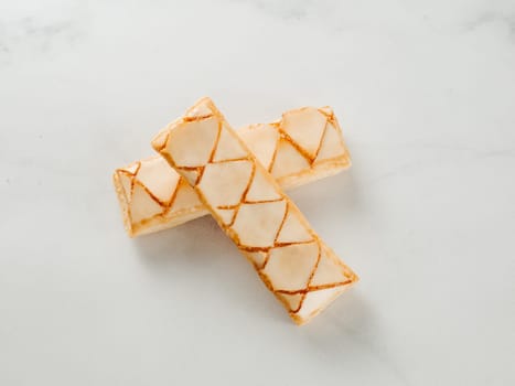 Italian crispy sweet bakery Sfogliatine glassate over white marble table surface. Tasty breakfast with apricot glaze puff pastries.