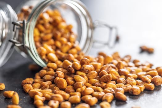 Roasted salted corn snack in jar on a black table.