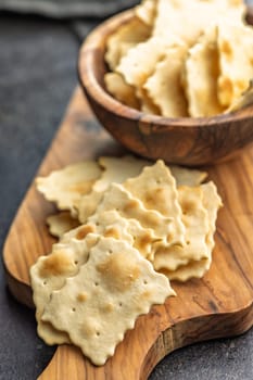 A crispy salted crackers on cutting board on a black table.