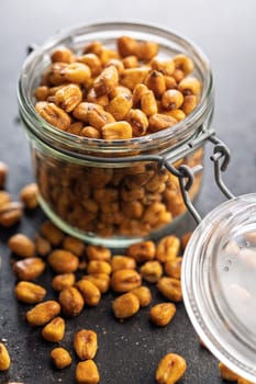 Roasted salted corn snack in jar on a black table.