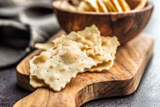A crispy salted crackers on cutting board on a black table.