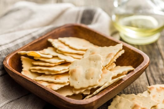 A crispy salted crackers in bowl on a wooden table.