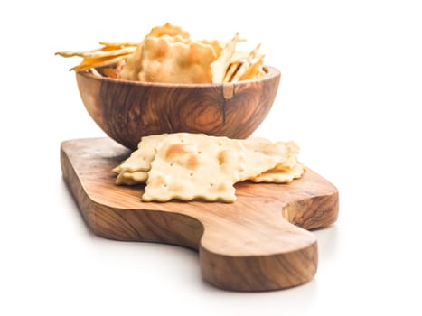 A crispy salted crackers on cutting board isolated on a white background.