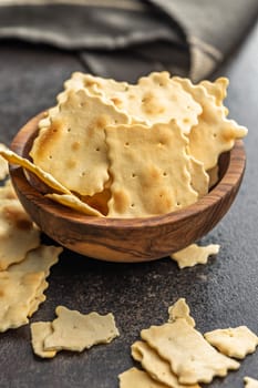 A crispy salted crackers in bowl on a black table.