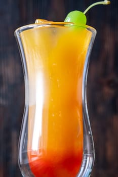 Banana Rum Punch cocktail garnished with green maraschino cherry