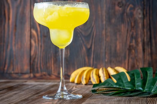 Frozen banana margarita cocktail on rustic wooden table