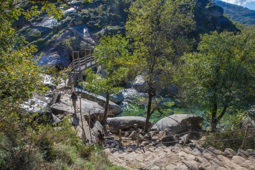 Trekkers about to cross the Los Pilones pedestrain bridge. Garganta de los Infiernos Reserve. Extremadura, Spain