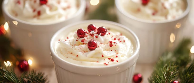 Creamy dessert topped with whipped cream and red sprinkles sits among holiday decorations creating a cozy Christmas atmosphere.