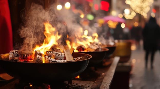 People gather around glowing fires on a lively street filled with holiday lights and decorations evoking a cozy Christmas atmosphere.