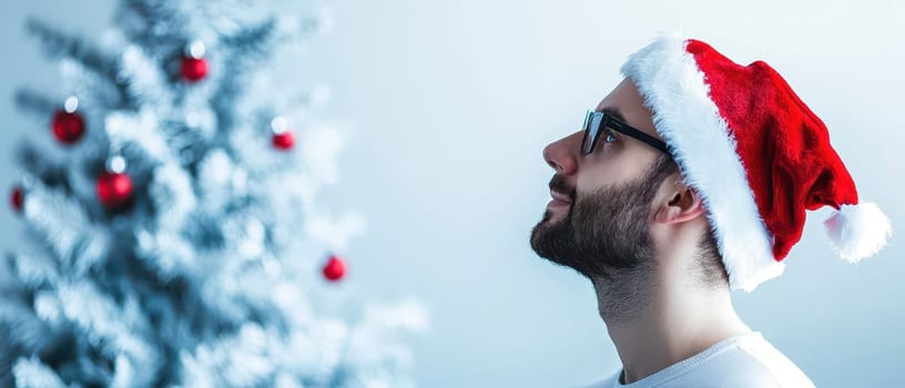 A man in a red Santa hat admires a decorated Christmas tree with shiny ornaments embracing the holiday spirit with joy and anticipation.