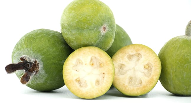 A group of fresh green feijoa fruits with two halves displayed on a white background, highlighting their juicy interior and vibrant color. Perfect for health, nutrition, and tropical fruit concepts.