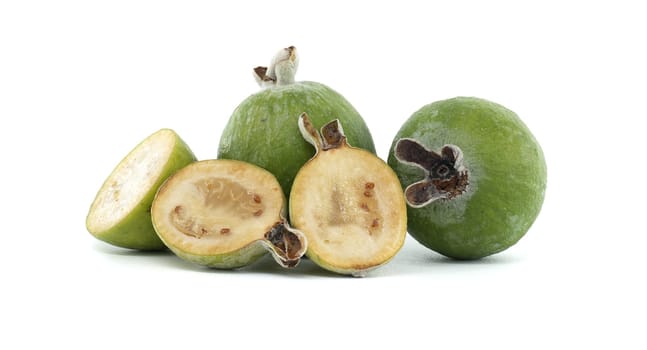 Close-up of whole and sliced feijoas on a white background, highlighting the fresh and juicy texture of this exotic fruit perfect for healthy eating and tropical recipes