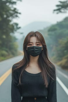 Young woman is wearing a protective face mask while standing on a road with trees in the background