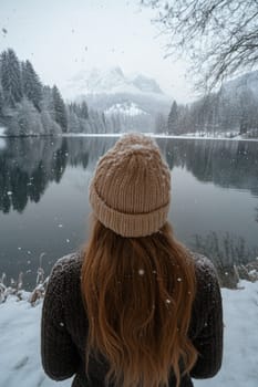 Woman wearing warm clothing is enjoying winter scenery by the lake on a snowy day