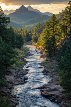 River is flowing through a valley filled with evergreen trees as the sun sets on the mountain peaks in the background