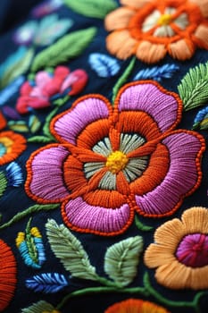 Colorful floral embroidery forming a floral pattern is laying on a black fabric, showing the details of its texture