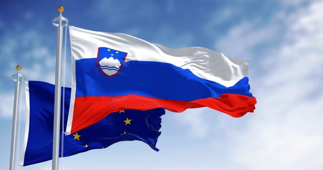 Flags of Slovenia and the European Union fluttering together on a clear day. Slovenia has been a member of the eurozone since January 1, 2007. 3D illustration render. Fluttering fabric