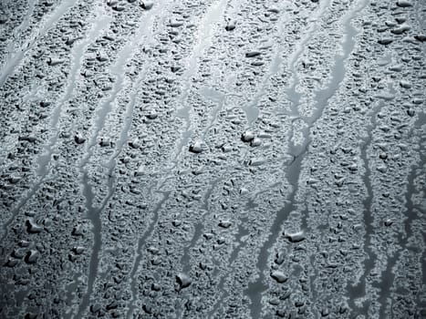 rain water drops on a bonnet of a black car during rainy day, full-frame closeup view