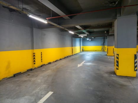 A spacious and well lit underground parking garage features bright yellow and gray walls for a modern feel