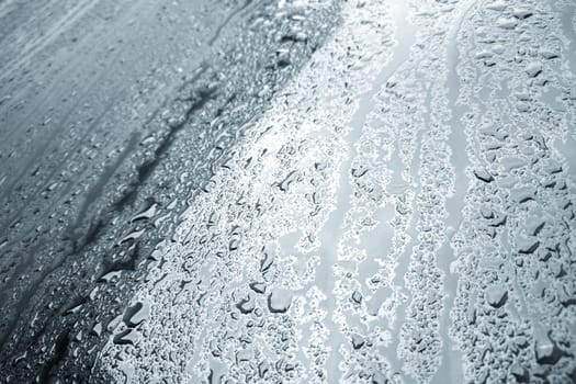rain water drops on a bonnet of a black car during rainy day, full-frame closeup view