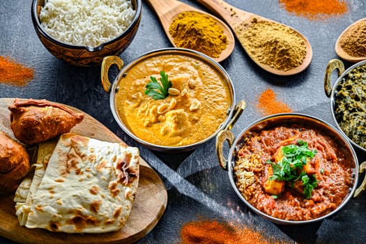 Composition with Indian dishes: madras paneer, palak paneer and shahi paneer with basmati rice served in original indian karahi pots