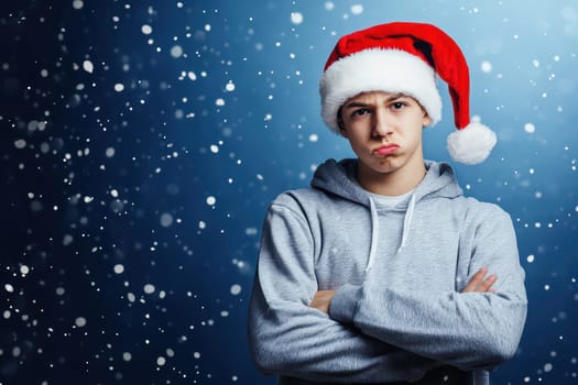 A young man wears a red and white Christmas hat crossing his arms with a serious expression amidst falling snowflakes.