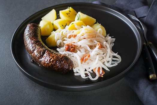 Bloody sausage morcilla, stewed sour turnip and potato close up. Traditional Slovenian dish with roasted bloody sausage