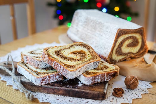 Christmas holidays celebration dessert. Potica, traditional Slovenian bread cake roll in front of christmas tree