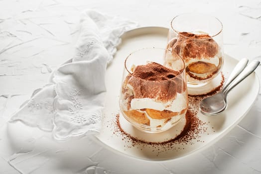 Traditional Italian dessert tiramisu in a glass cup. Homemade tiramisu in glass cup, step by step cooking process. Traditional unbaked Italian dessert