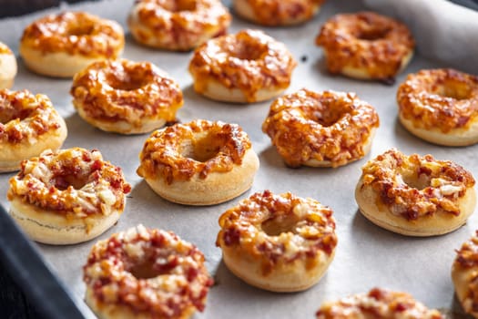 Mini pizza bagels on a baking paper.