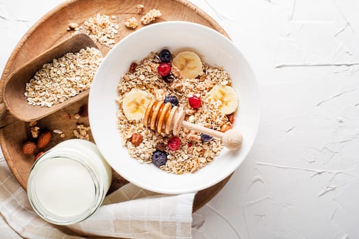 A bowl of dry granola and muesli served with fresh fruit and nuts. Traditional Oatmeal plate. Healthy food, diet. Top view.