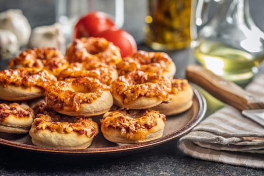 Mini pizza bagels on plate on a black table.
