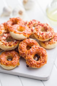 Mini pizza bagels on cutting board on a white table.