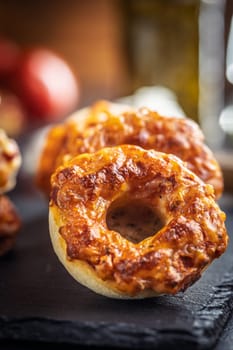 Mini pizza bagels on cutting board on a black table.