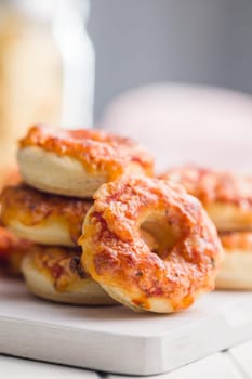 Mini pizza bagels on cutting board on a white table.