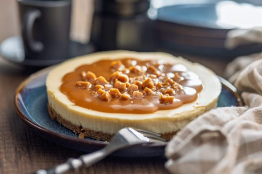 Cheesecake with caramel topping on plate on a wooden table.