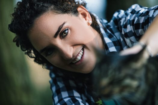 Caring vet examines a cat in a forest, radiating love and kindness in nature's beauty. Sunlight filters through trees, creating a trusting atmosphere