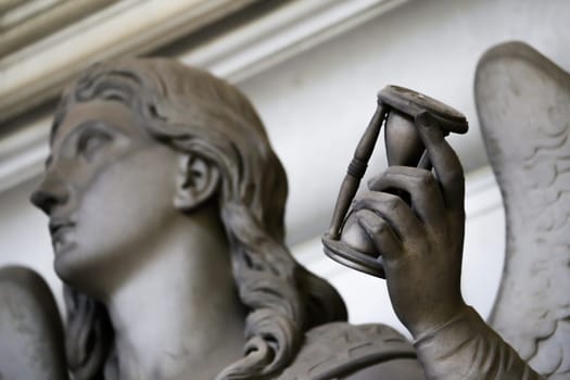 Antique statue holding a sandglass. Concept of time passing, countdown, retro hourglass