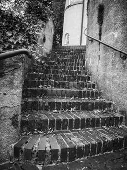 Old brick staircase on a ruin wall with railing in black and white.