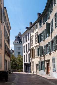 A narrow street with a castle of Henry VI in the background. The street is lined with buildings and has a lot of windows, Pau, France