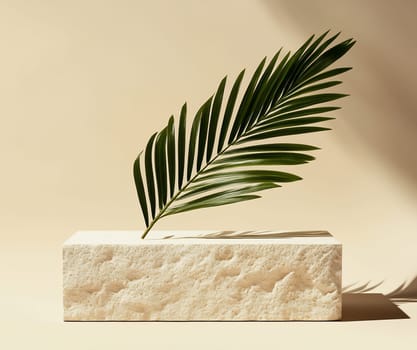 A single green palm leaf is gracefully positioned on a textured stone block against a soft beige backdrop, showcasing minimalist decor.