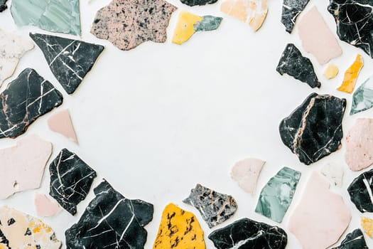 Various shaped stones in shades of black, pink, green, and yellow create a vibrant mosaic border around a light center.