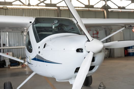 Small private lightweight propeller airplane in hangar, closeup photo